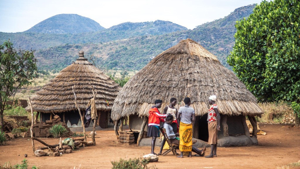 Traditional thatched manyatta homestead and community with mountains, Karamoja region Uganda