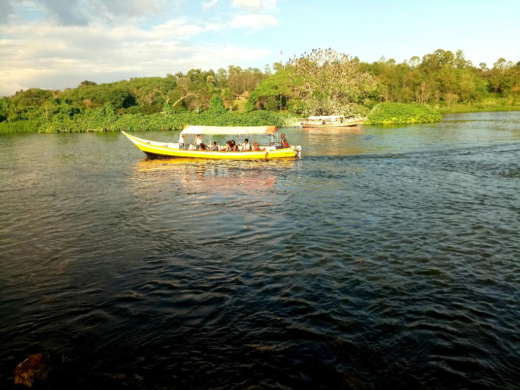 Tour boat on the Nile with lush green riverbank, Jinja Uganda